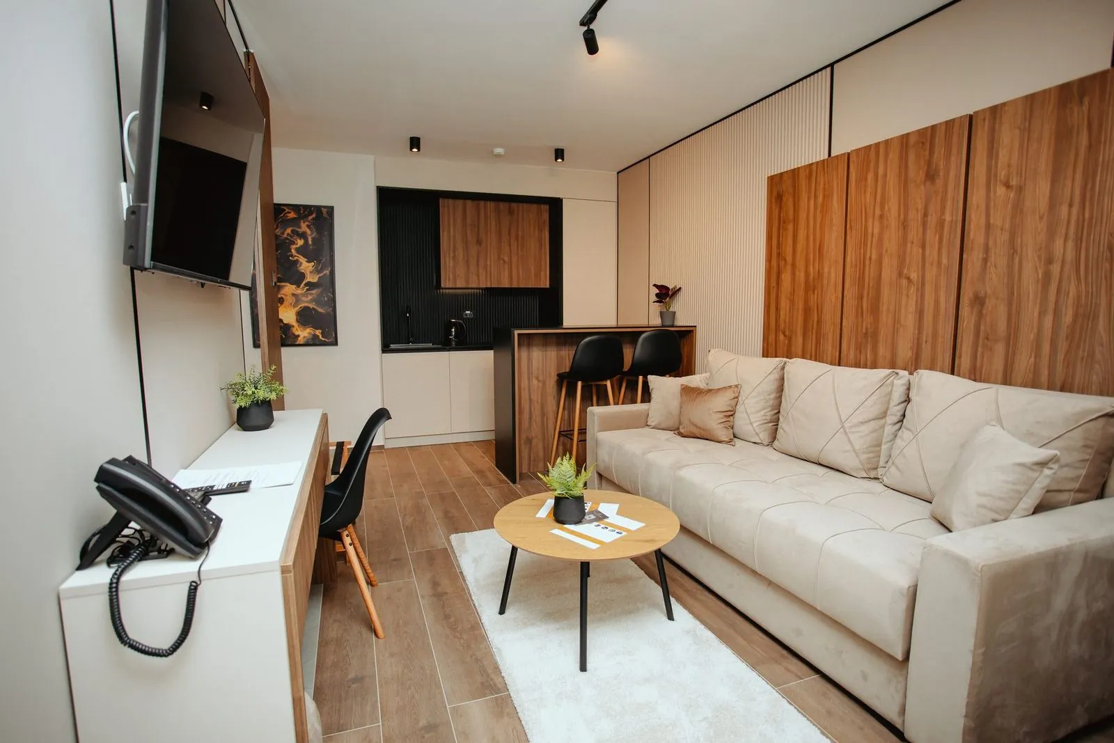 Dnevni deo apartmana sa radnim stolom i kuhinjom u pozadini