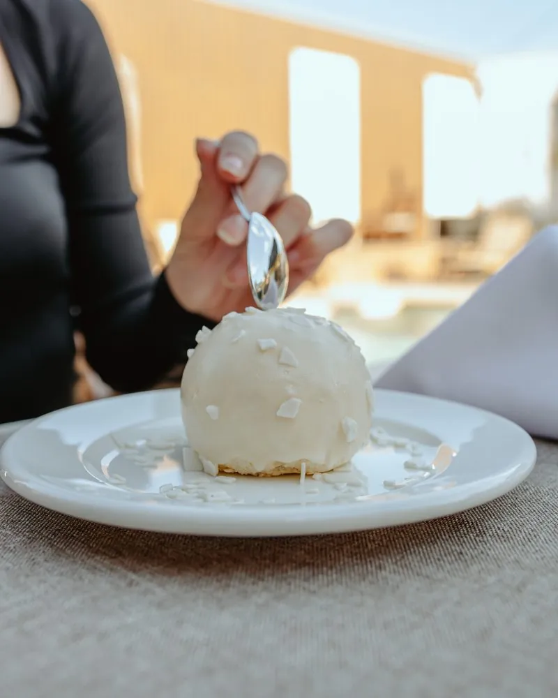 White dome-shaped dessert on a plate with a spoon