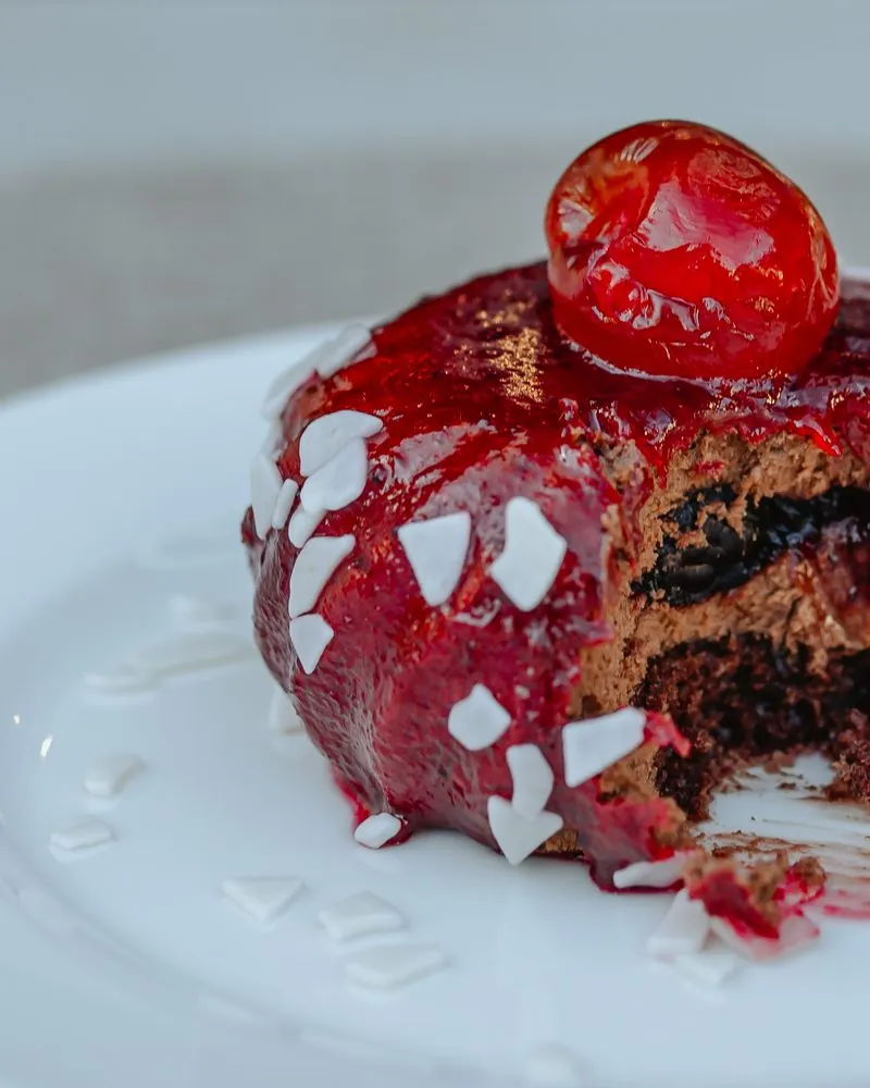 Dessert with red glaze and a cherry on top, cut open