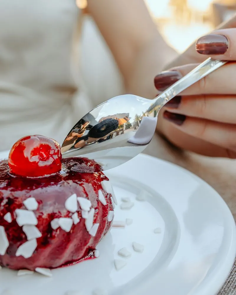 Dessert with red glaze and a cherry, spoon in hand