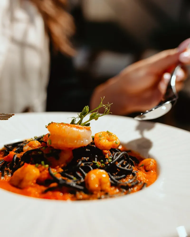 Black pasta with prawns on a white plate