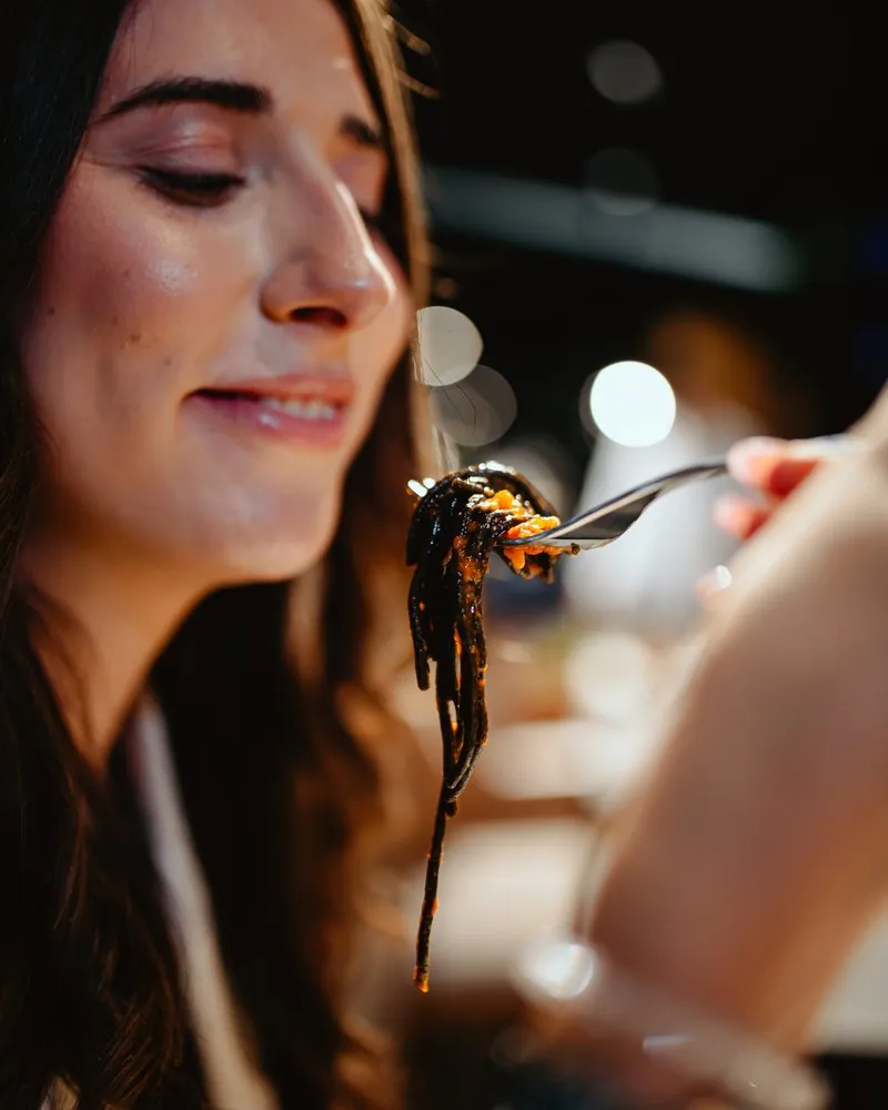 Restaurant guest with a forkful of black pasta